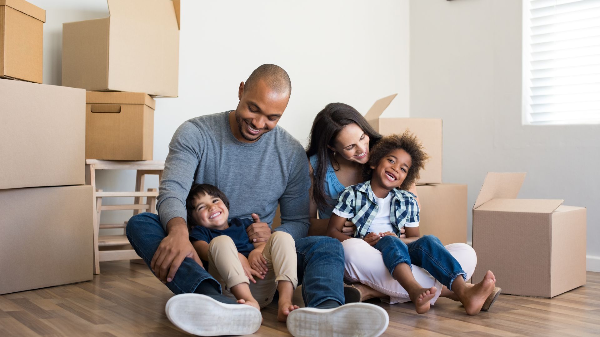 smiling family of four surrounded by moving boxes