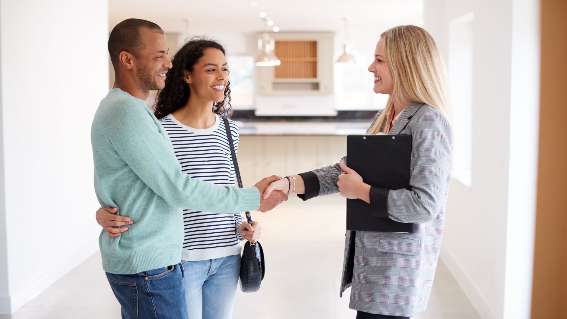 two tenants shaking hands with a property manager in an empty apartment