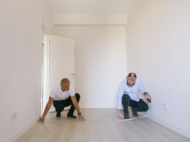 two peole measuring a hallway