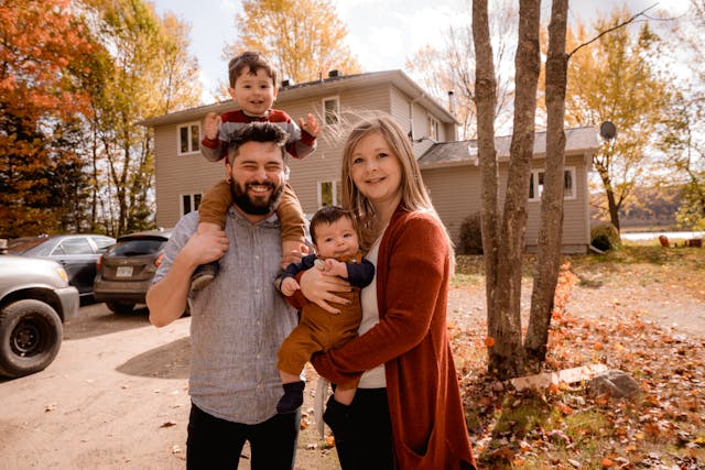 family of four standing in front of home