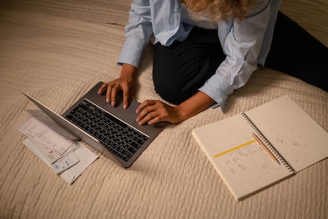 person using a laptop next to a cheque book